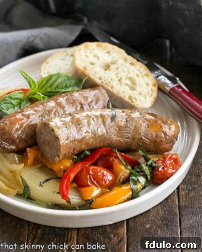 A perfectly cooked plate of Sheet Pan Sausage and Peppers, served with rustic bread and a red-handled fork, ready for a comforting meal.