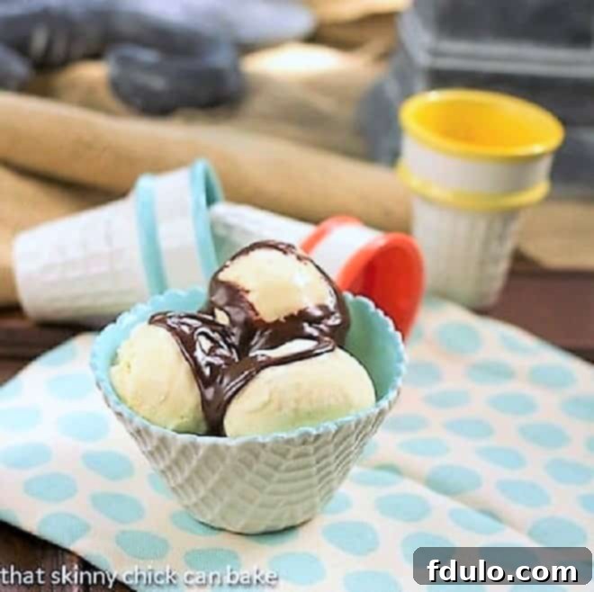 Close-up of creamy Vanilla Bean Ice Cream served in a textured cone-shaped bowl, generously topped with warm, glossy hot fudge sauce.