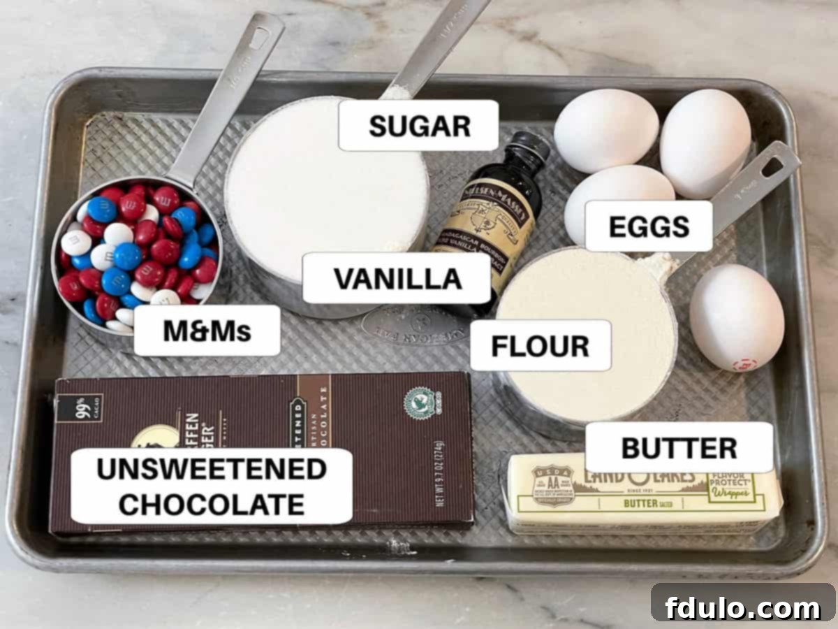 An overhead shot showcasing all the essential ingredients for making chewy brownie cookies, neatly arranged with labels on a sleek metal sheet pan.