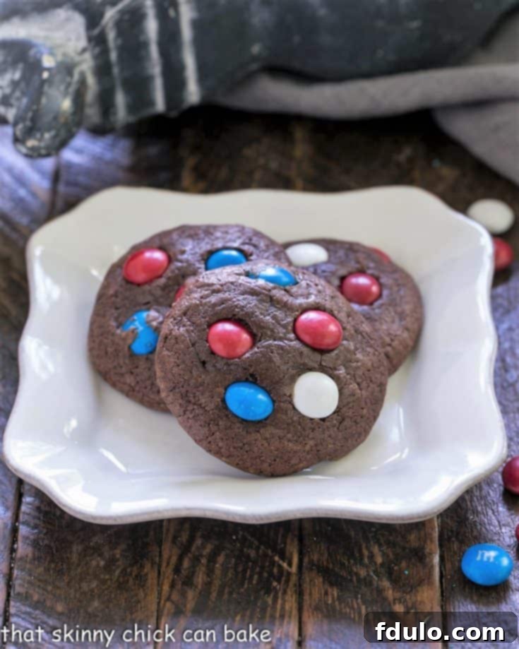 Three perfectly baked 4th of July cookies on a white plate, adorned with festive M&M's.