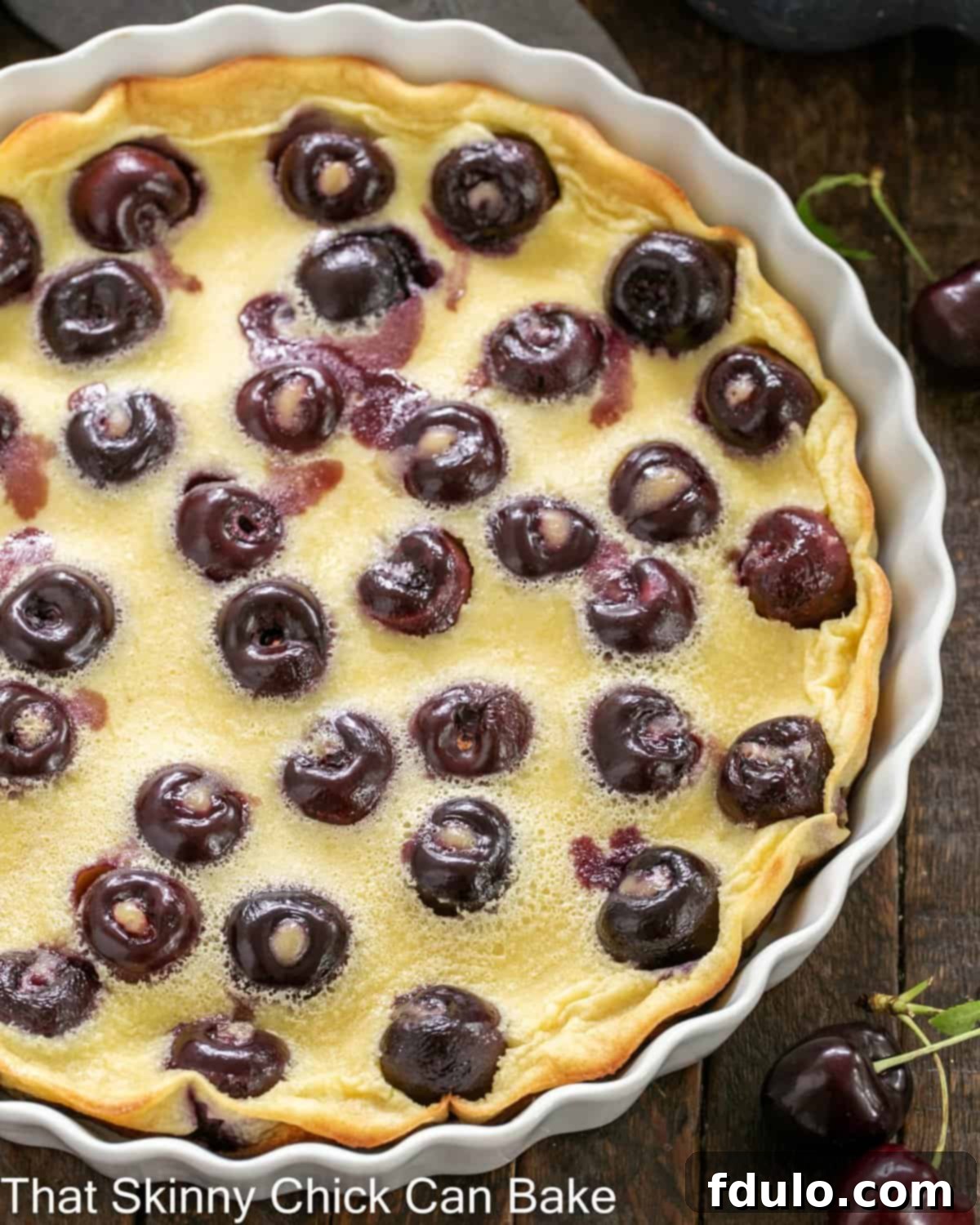 Overhead view of cherry clafoutis in a shallow white souffle dish.