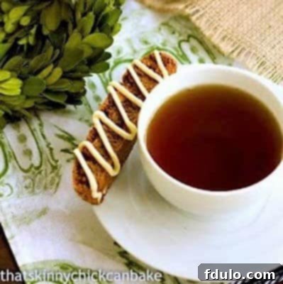 Crispy Gingerbread Biscotti on a white teacup saucer, perfect for dipping into a warm drink.