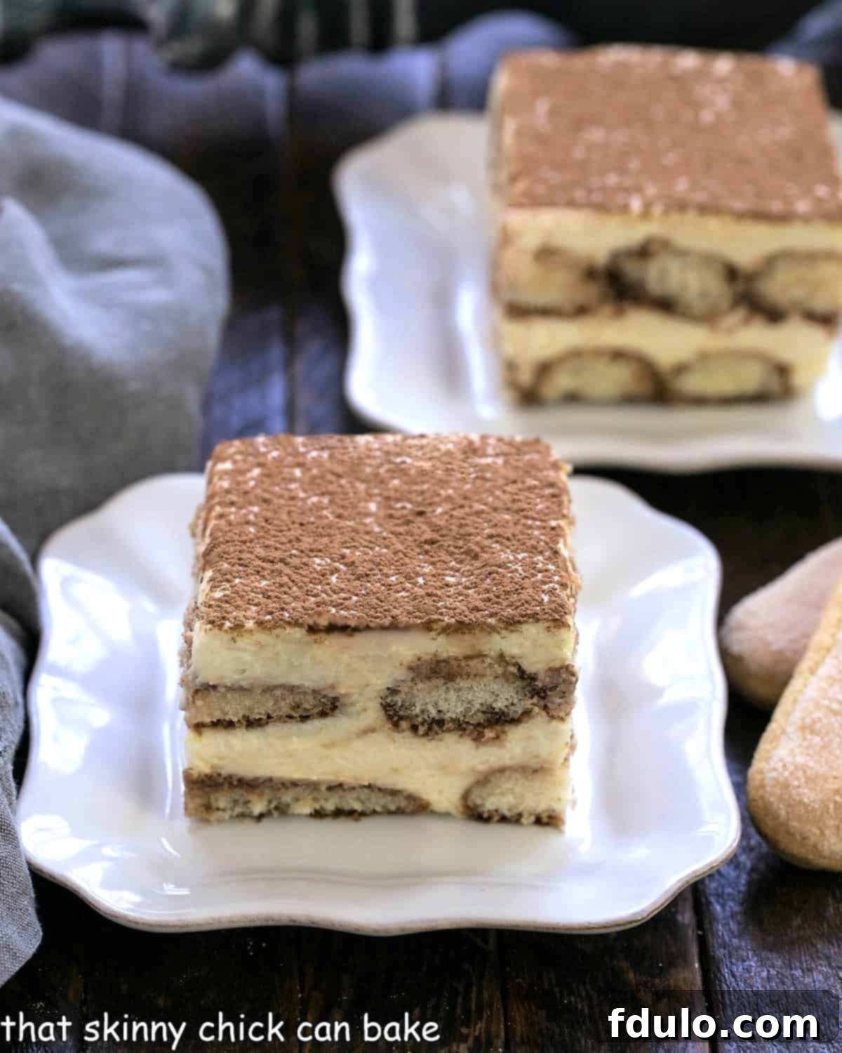 Unlock the Secret to Perfect Tiramisu 2 Two slices of tiramisu on square white plates with tips of 2 ladyfingers visible on the side.
