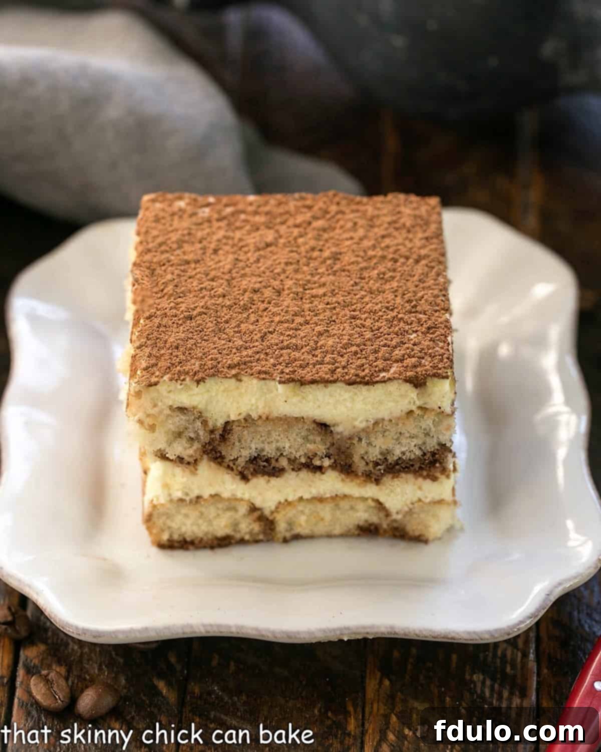 Unlock the Secret to Perfect Tiramisu 6 A slice of tiramisu on a square white plate.