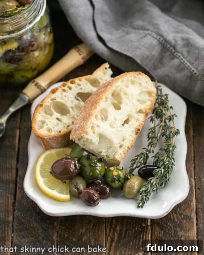 Herbed olives on a white plate with bread and fresh thyme, showcasing the vibrant colors and fresh herbs