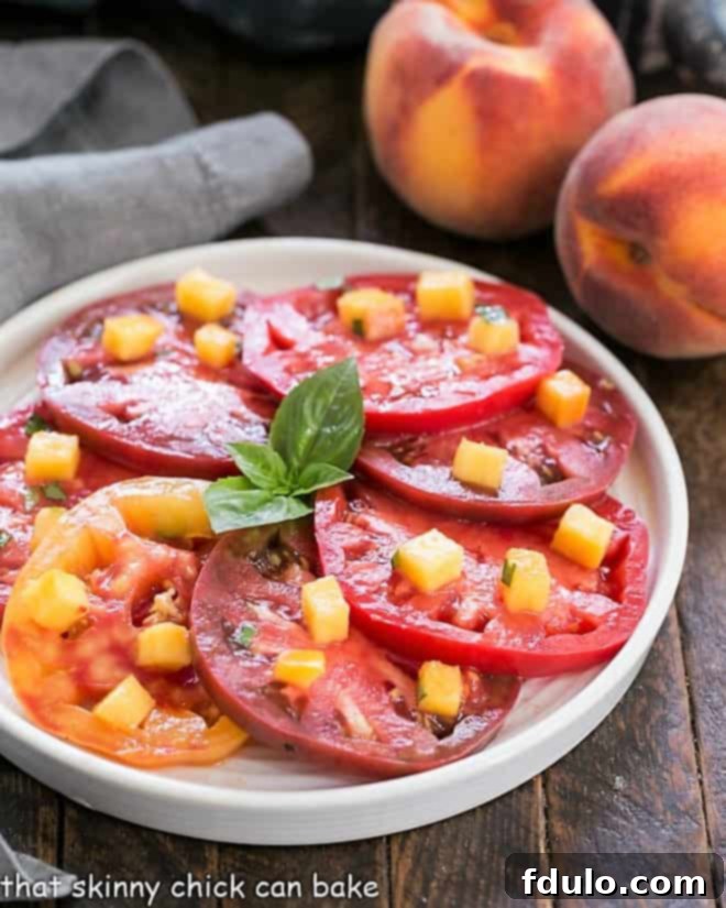 A vibrant tomato salad with a peach vinaigrette served on a round white plate, highlighting the fresh colors of summer produce.