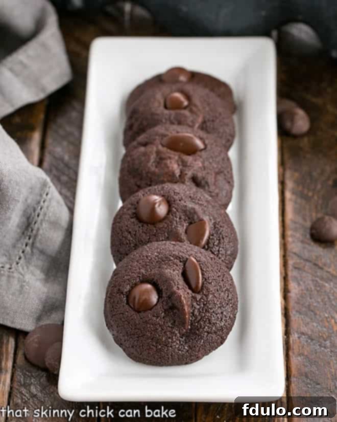 Perfectly baked double chocolate chip cookies arranged neatly on a narrow white serving tray, showcasing their rich color and inviting texture.