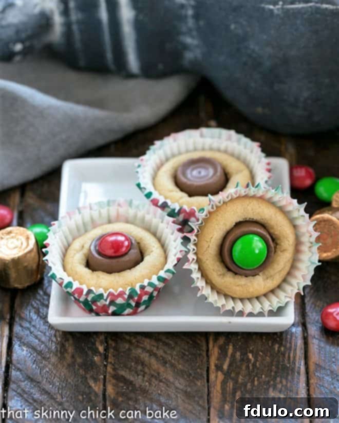 An assortment of freshly baked peanut butter cookie cups with various candy fillings on a square white plate