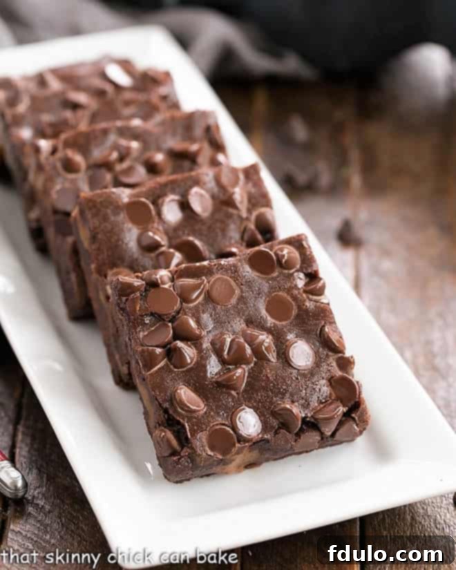 Front view of a beautiful platter of chocolate caramel brownies on a white serving tray, perfectly cut and arranged.