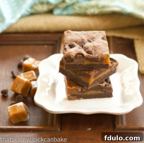 Layered Caramel Brownies neatly stacked on a square white plate, with visible caramel and chocolate sections.
