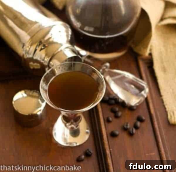 Homemade Kahlua in a glass next to a carafe of Kahlua, showcasing its rich, dark color and inviting aroma.