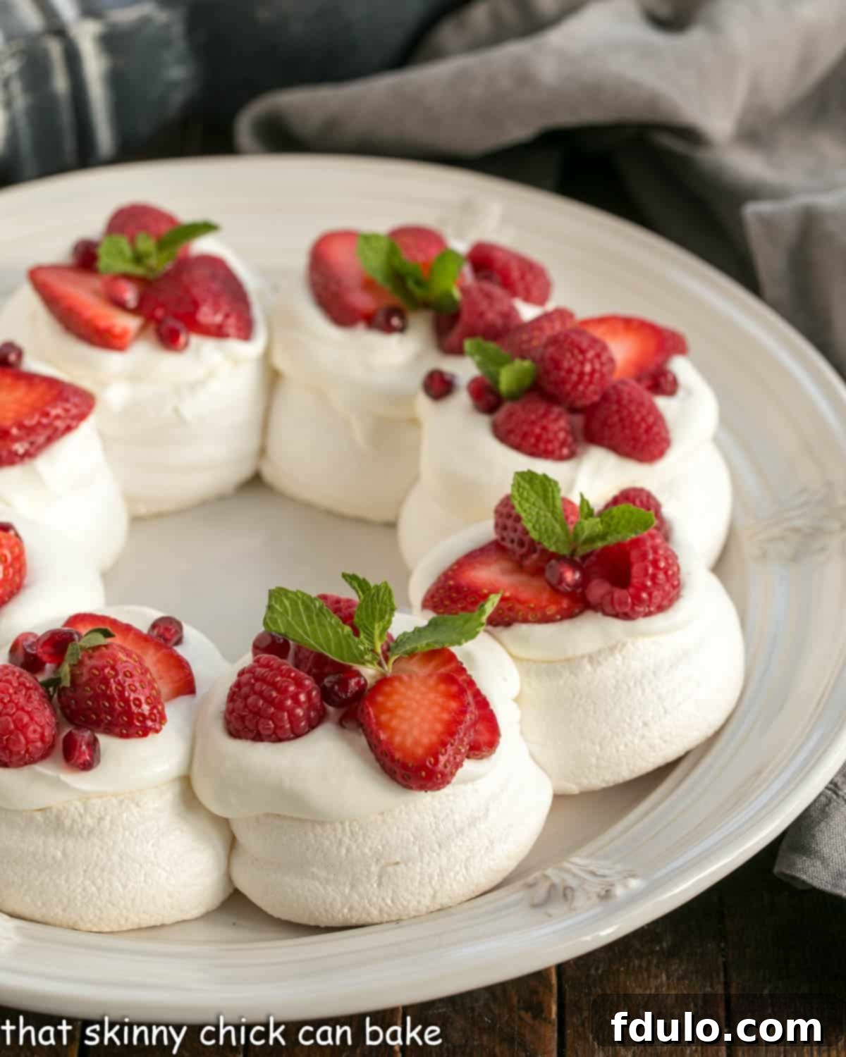 Pavlova Wreath topped with berries and cream on a white serving plate, ready for a festive celebration.