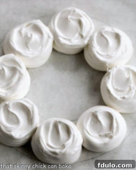 Undecorated pavlova wreath on a parchment lined baking sheet, ready for the oven.