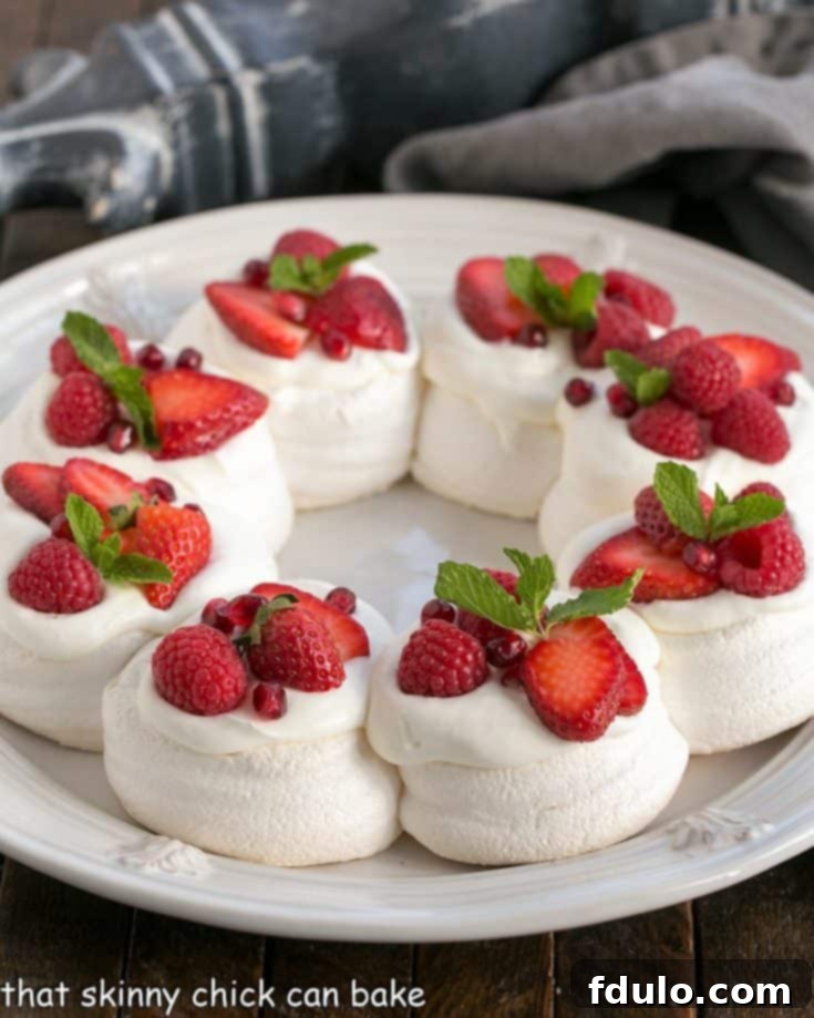 Christmas Pavlova on a white plate topped with red berries and mint