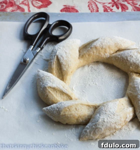 Whole Wheat Wreath dough being prepared, showing cuts made with kitchen shears to form the distinctive wreath shape before baking.