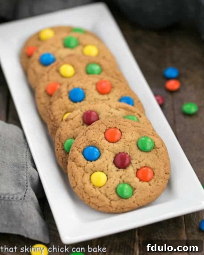 Classic M & M Cookies lined up on a white rectangular tray, showing their perfectly round shape.