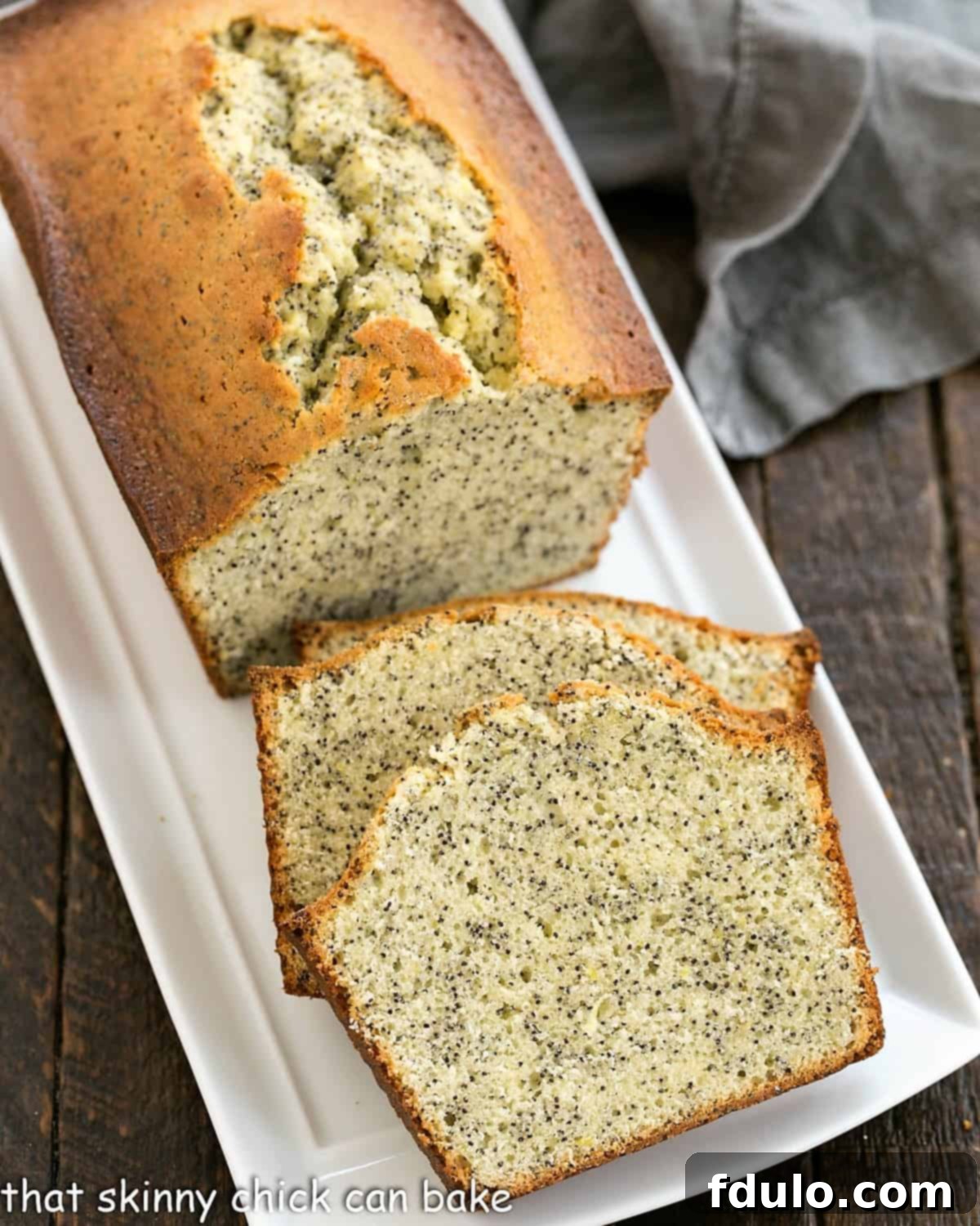 Sliced lemon poppy seed loaf on a white ceramic tray.