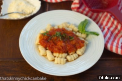 Ricotta Gnocchi with Marinara on a white plate with a basil garnish.